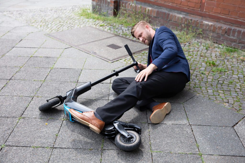 An e-scooter rider lies on the footpath after having an accident